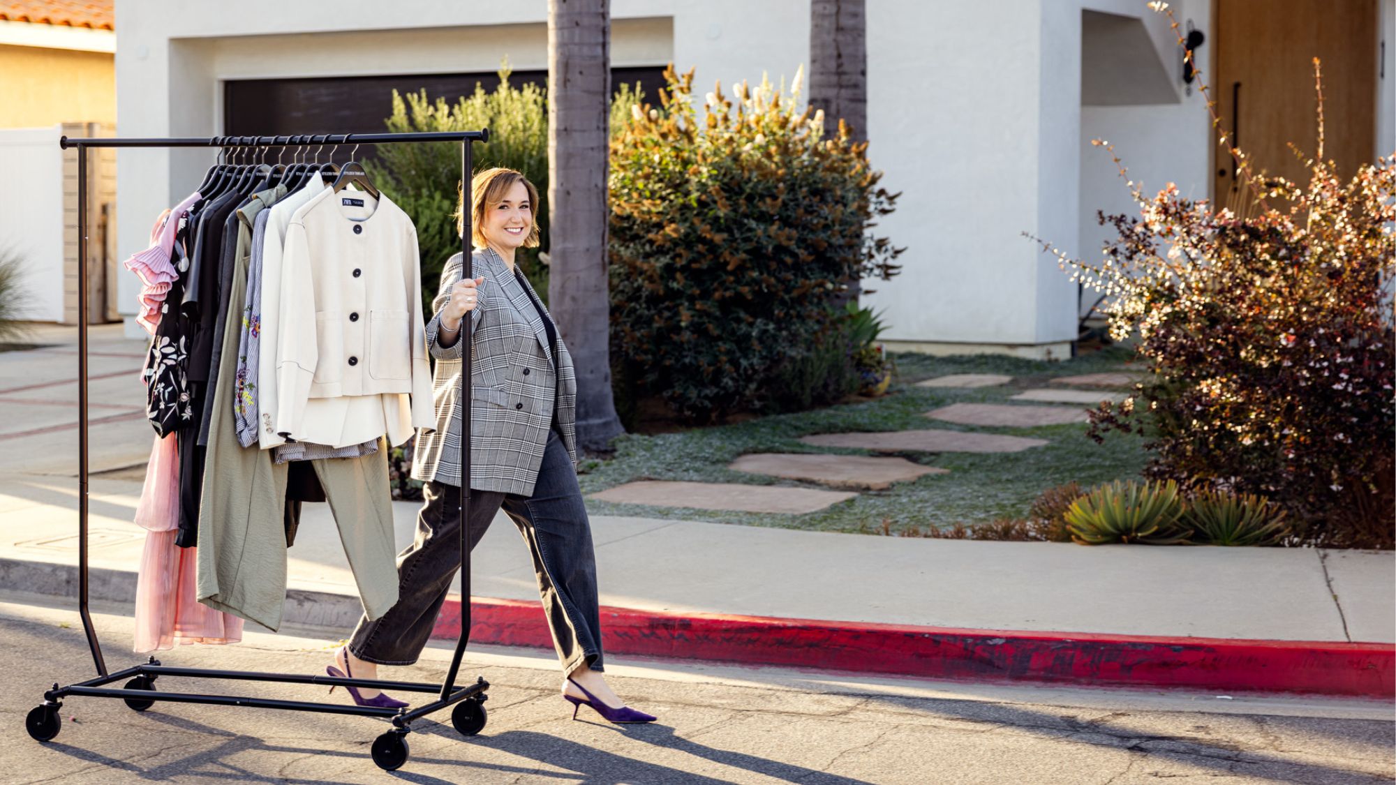 Heather Chee, women's personal stylist in Orange County, rolling a curated clothing rack for a client.
